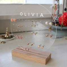 a clear acrylic display with earrings in it on a table next to flowers