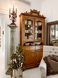 a living room filled with furniture and a christmas tree in front of a china cabinet