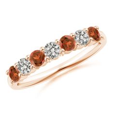 an orange and white diamond ring with three stones on the side, set in yellow gold