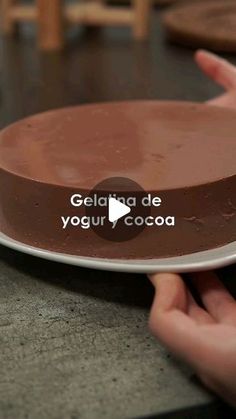 someone holding a plate with a chocolate cake on it that says gelato de yogurt cocoa