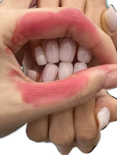 a woman's hands holding out her mouth with pink lipstick on the top and bottom