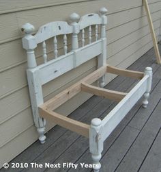 a white bed frame sitting on top of a wooden floor next to a house wall