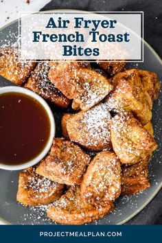 an air fryer french toast bites on a plate with syrup and powdered sugar