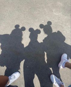 three people standing next to each other with their shadows on the ground in front of them