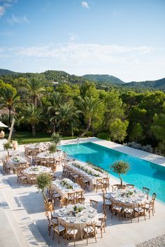 an outdoor dining area with tables and chairs next to a swimming pool surrounded by trees