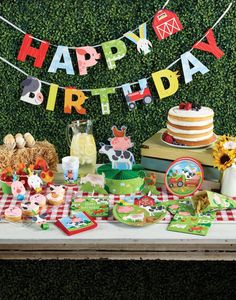 a table topped with lots of cakes and desserts next to a green hedge wall