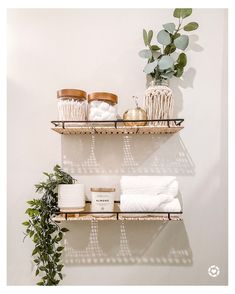 two shelves with towels, candles and other items on them next to a potted plant