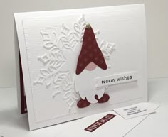 a white card with a red santa hat on it's head and the words warm wishes