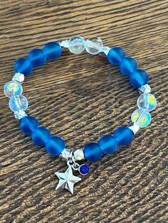 Blue and Clear beads with sliver accents and a star charm and blue gem  7 in or 17.78 cm Strong, Stretchy, and Durable     Very pretty bracelet for any occasion for any day Blue Beaded Bracelets With Star Charm For Gift, Blue Beaded Star-shaped Bracelets, Blue Beaded Bracelets With Star Charm, Blue Bracelets With Star Charm And Round Beads, Blue Bracelet With Star Charm As Gift, Blue Handmade Star-shaped Beaded Bracelets, Blue Bracelets With Star Charm For Gift, Handmade Blue Star-shaped Bracelet, Handmade Blue Star Bracelet