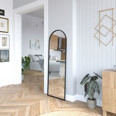 a room with white walls and wood flooring has a large mirror on the wall