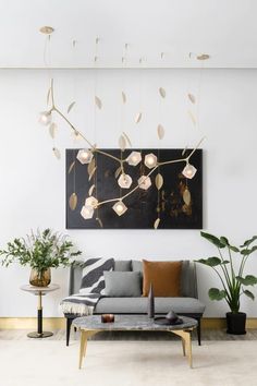 a modern living room with white walls and plants hanging from the ceiling, in front of a painting on the wall