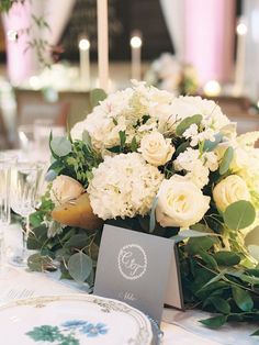 a table set with white flowers and greenery