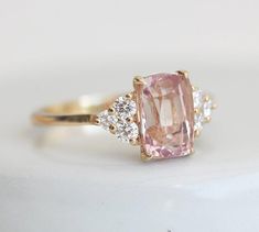 a pink diamond ring with three diamonds around it