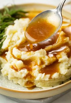 a spoon full of gravy on top of mashed potatoes