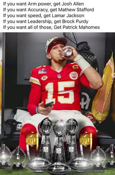 a man drinking from a bottle while sitting on top of a bench with trophies in front of him