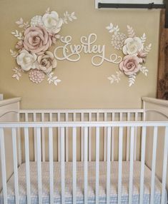 a white crib in front of a wall with flowers and the word ewety on it