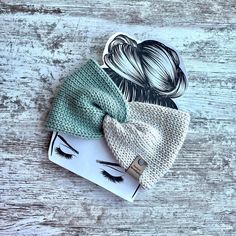 three knitted hair accessories on top of a wooden table, one with a ponytail and the other with eyelashes