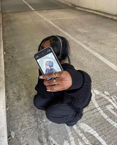 a woman kneeling on the ground holding up her cell phone to take a selfie