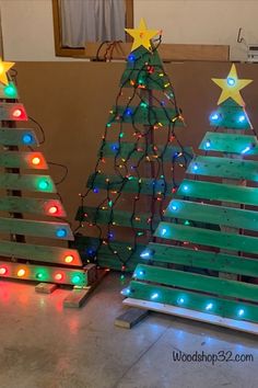 three wooden christmas trees with lights on them