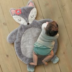 a toddler is playing with a stuffed animal on the floor next to a rug