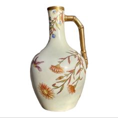 a white and gold vase with flowers painted on the side, in front of a white background