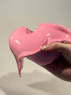 a hand holding a pink object with white background