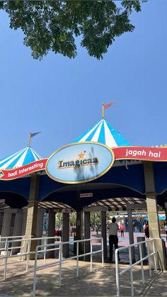 the entrance to an amusement park with blue and white umbrellas on it's roof