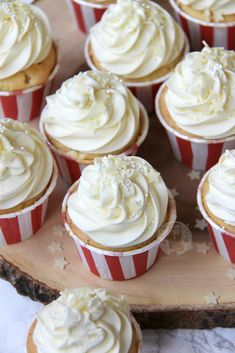 cupcakes with white frosting sitting on a wooden platter