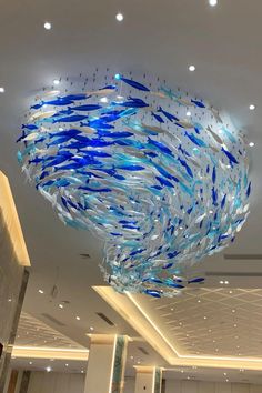 a large chandelier hanging from the ceiling in a lobby with blue glass fish on it