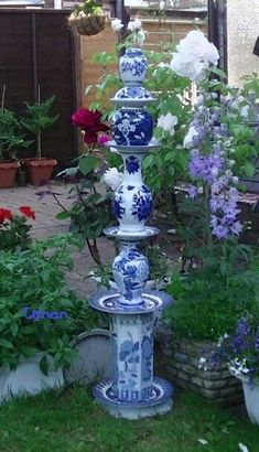 there are many blue and white vases in the garden with flowers around them,