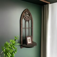 a green wall with a wooden shelf on it and a potted plant in the corner