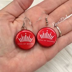 a pair of red earrings with the words king of beers printed on them