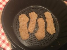 four pieces of meat cooking in a frying pan on a checkered table cloth