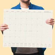 a man holding up a large calendar in front of his face