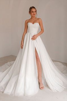 a woman wearing a white wedding dress with high slit