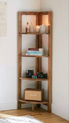 a wooden shelf with books and other items on it in a corner next to a white wall