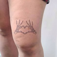 two hands making a heart shape with their fingers tattoo on the thigh and leg area