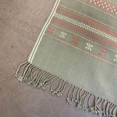 a gray and red rug with fringes on top of the floor next to a wall