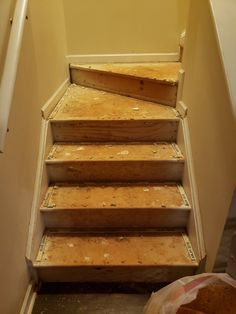 a set of wooden steps leading up to the top of a flight of stairs in an unfinished room