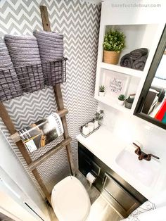 a bathroom with a toilet, sink and ladder in it's corner area next to a mirror