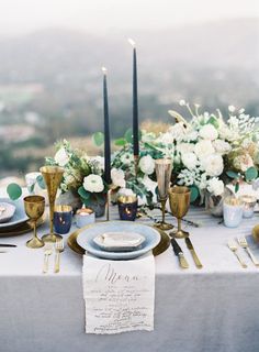 an elegant table setting with candles, flowers and napkins on top of the table