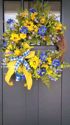 a wreath with yellow and blue flowers hanging on a door