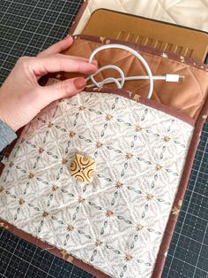 someone is working on an item that looks like a quilter's block with scissors and thread in it