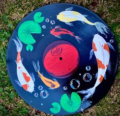 a frisbee painted with koi fish and bubbles on the grass in front of it