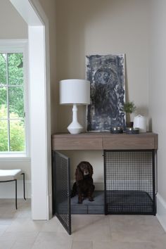 a dog is sitting on the floor under a table with his caged door open