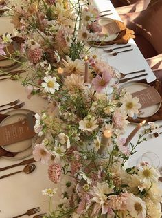 the table is set with flowers and place settings for guests to sit down at it