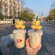 two plastic cups with yellow rubber ducks on top, one holding a drink and the other holding a straw