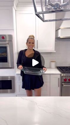 a woman standing in a kitchen holding a tray