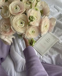 a bouquet of flowers is being held up by someone's hand on a bed