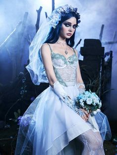 a woman in a white dress and veil with flowers on her head is posing for a photo